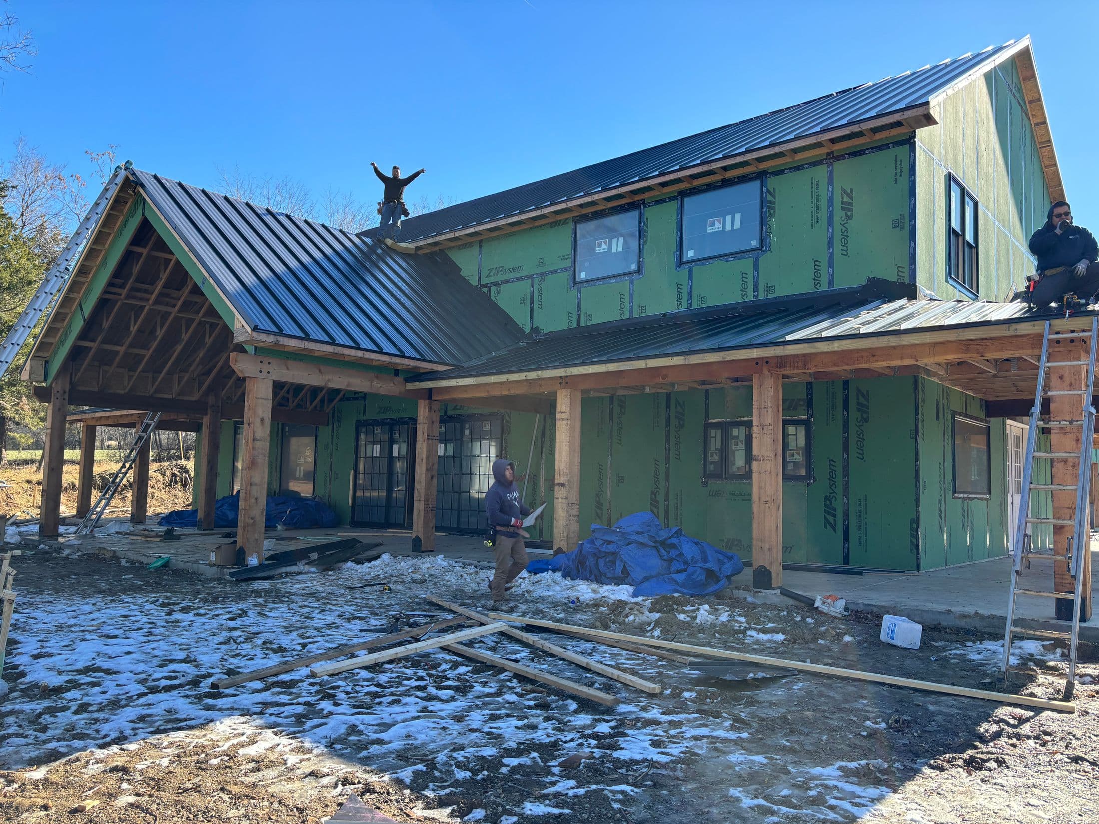 Crew sheathing and roofing a barndominium during winter